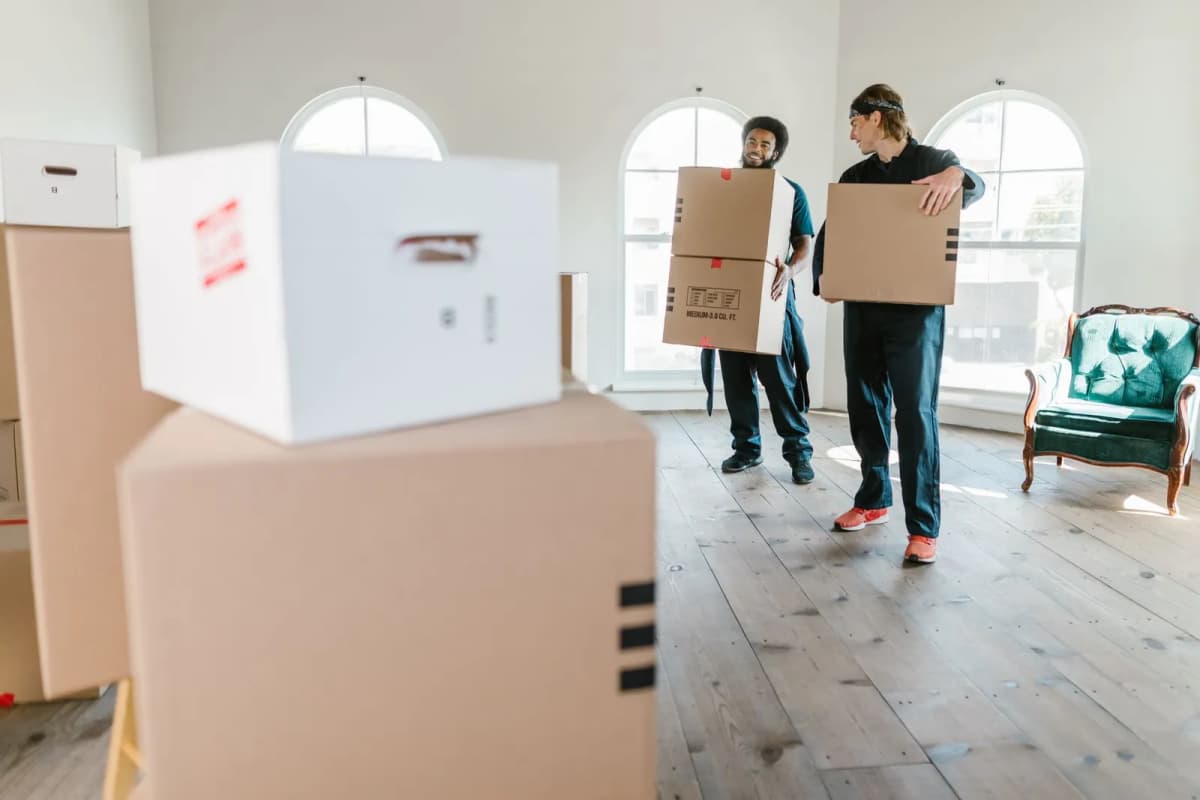 Two movers carrying boxes into a home