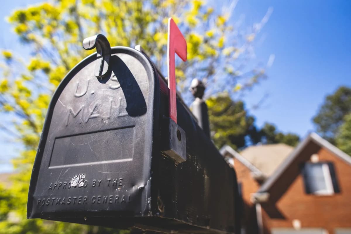 Close-up of a traditional US mailbox with the red flag raised, on a residential street
