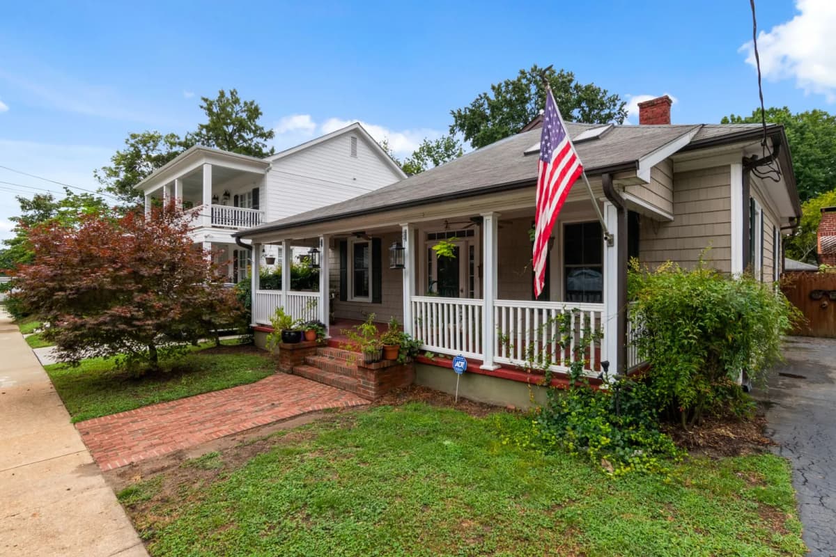 A single-family bungalow with a front porch and an American flag