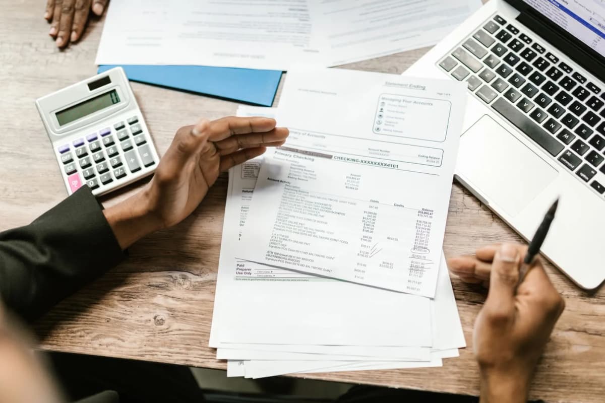 Financial documents, a calculator and a laptop on a desk