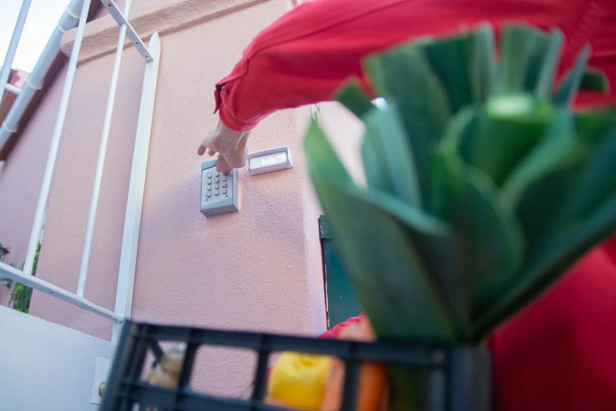 A person entering a code on a keypad at a residential gate