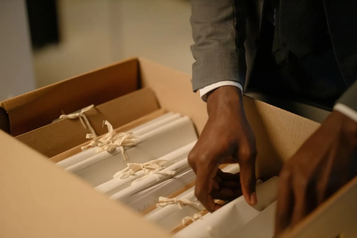 A person arranging tied bundles of documents in an archive box