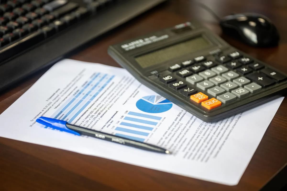 A calculator, a pen and a printed financial report on a desk