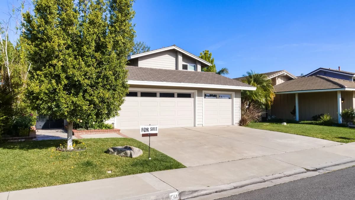 A suburban house with a for-sale sign in the front yard