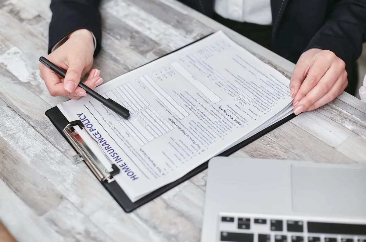 Hands reviewing a home insurance policy document with a pen