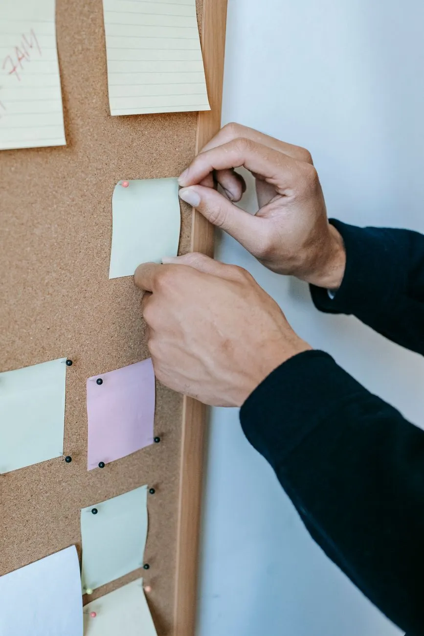 Hands pinning notices to a cork board
