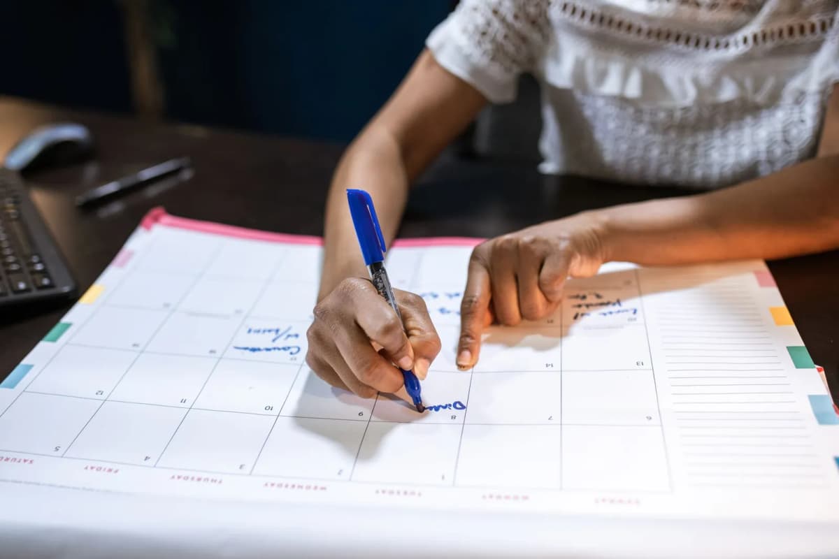 A person marking dates on a desk calendar