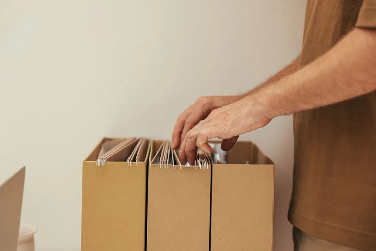 A person sorting documents into cardboard file boxes