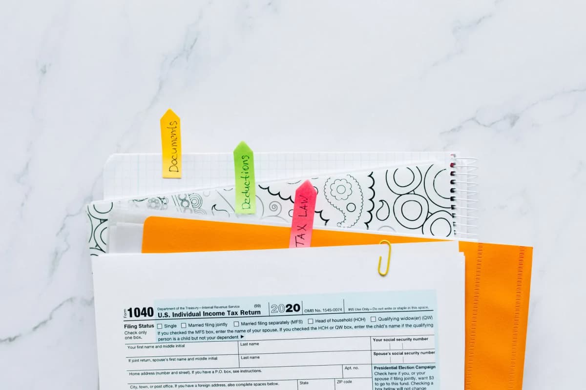 Financial and tax documents organized with colored tabs on a table