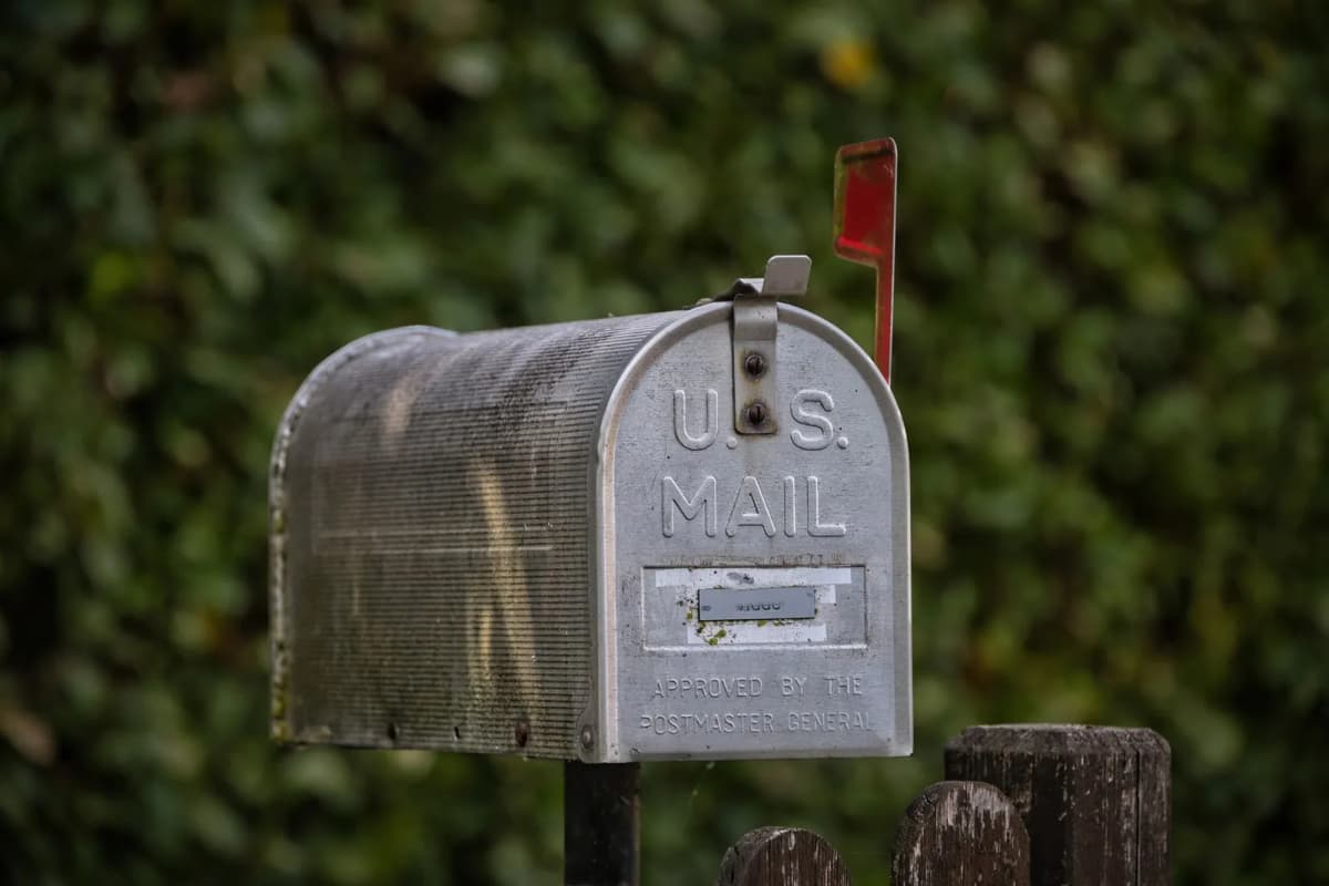 A metal U.S. Mail curbside mailbox with its red flag raised