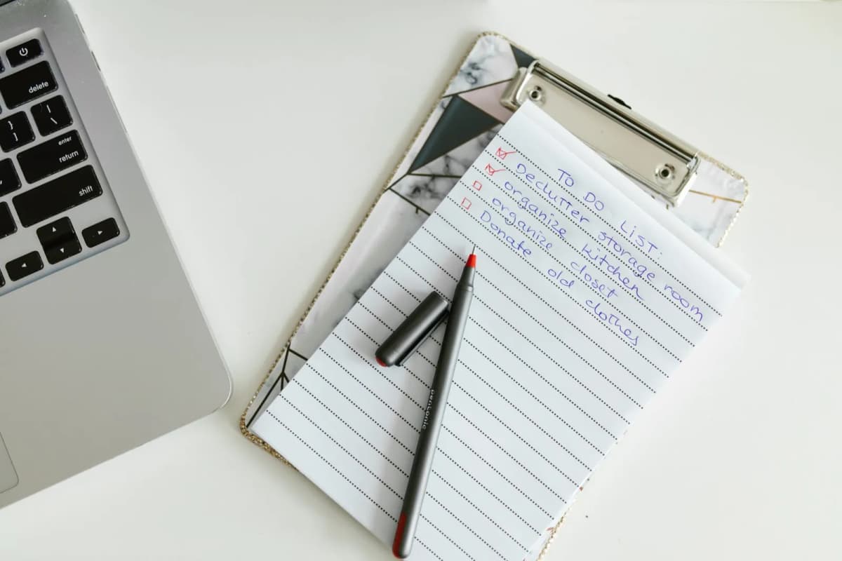 A to-do list on a clipboard beside a laptop and pen