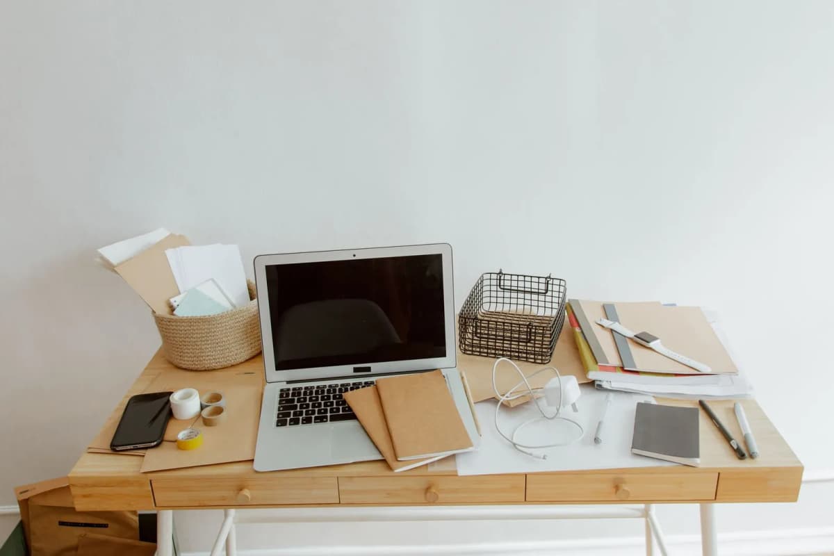 A tidy home desk with a laptop, notebook and supplies