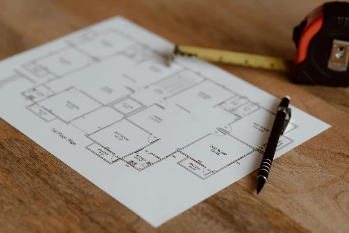 Architectural plan on a wooden surface with a pen and ruler