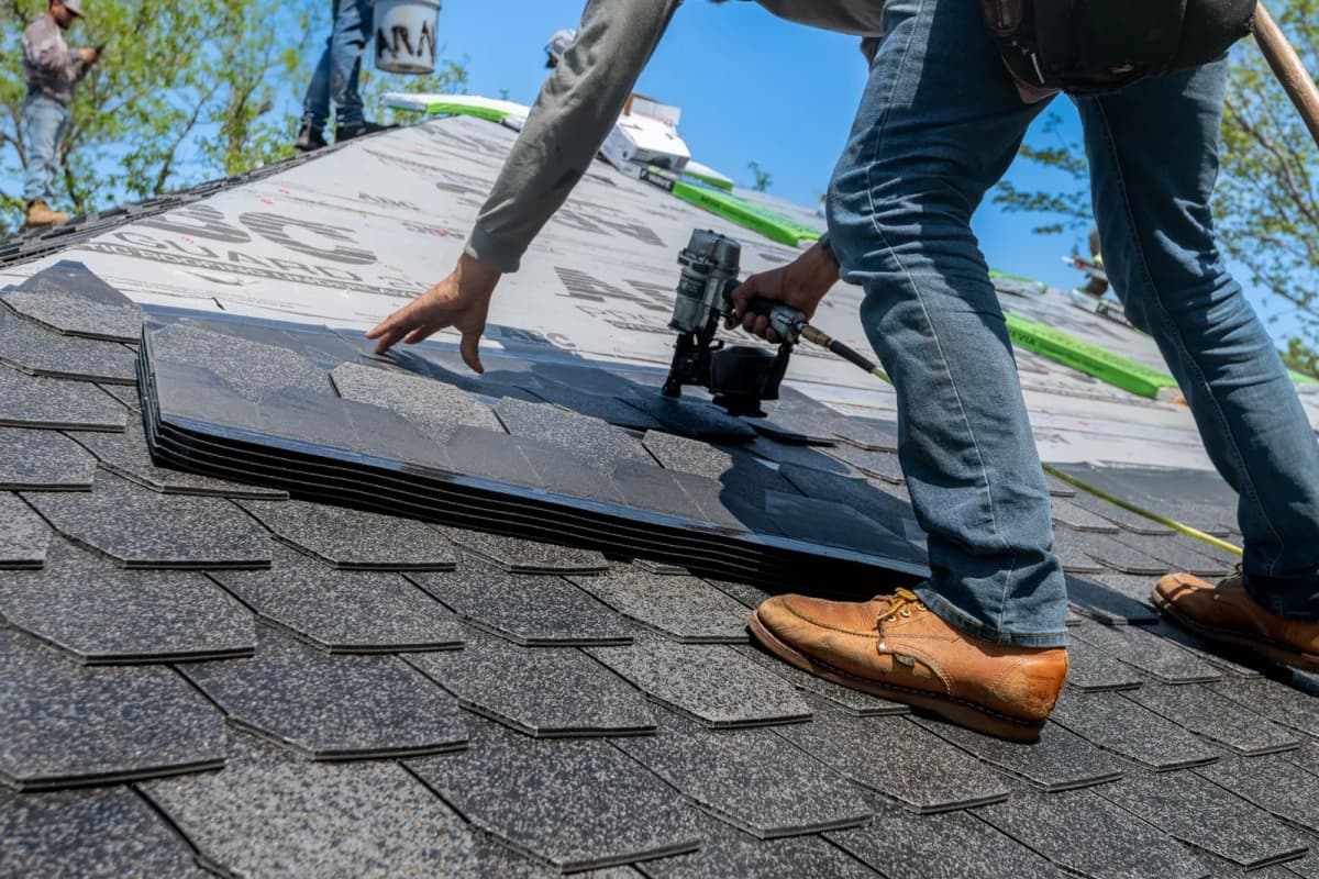 A roofer installing shingles on a residential roof