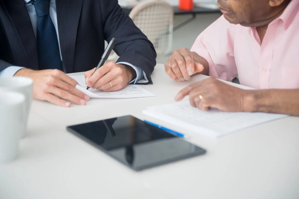 Two people signing documents at a desk