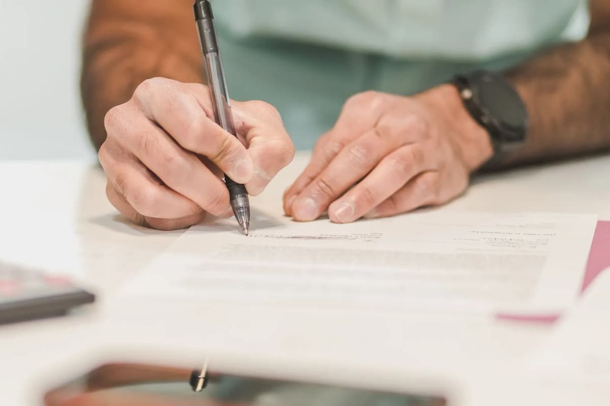 A person signing an official document at a desk