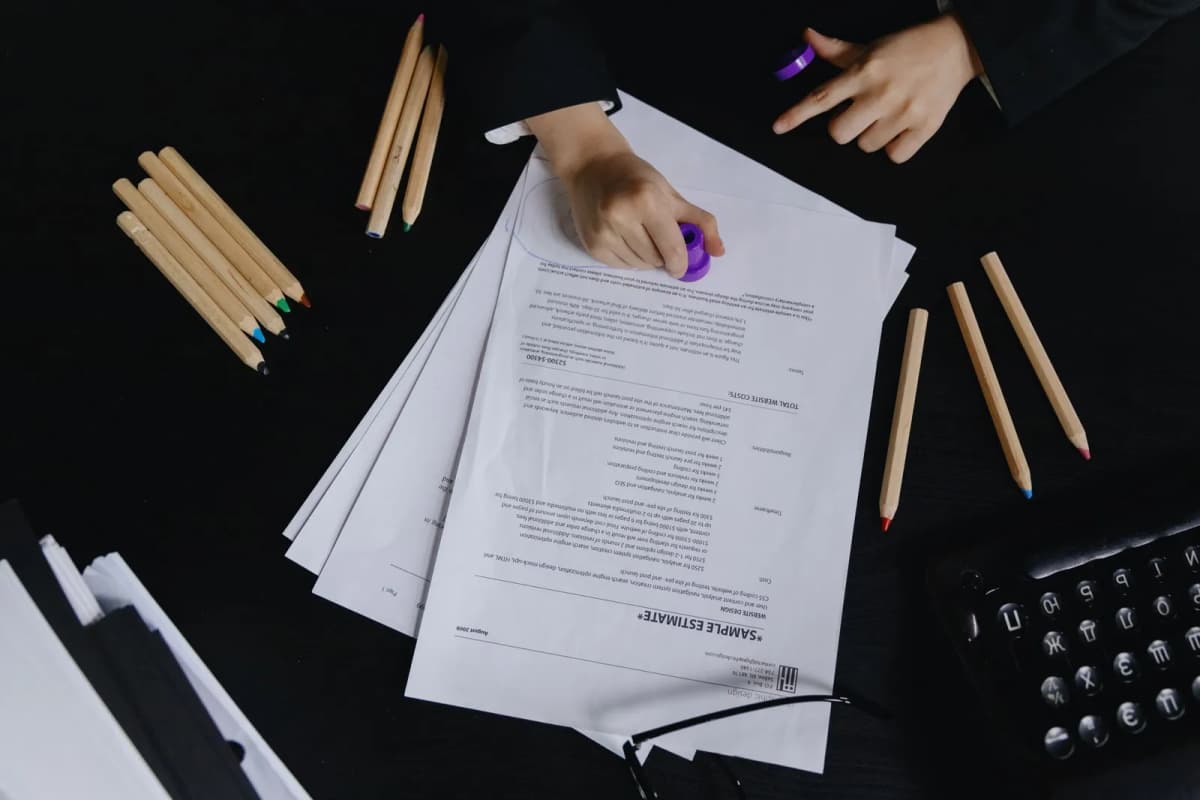 Hands working through a stack of printed application pages at a desk