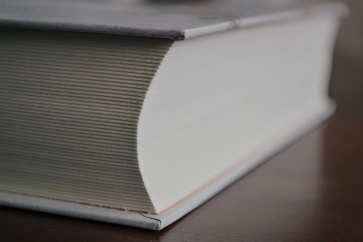 A thick hardcover rulebook lying closed on a wooden table