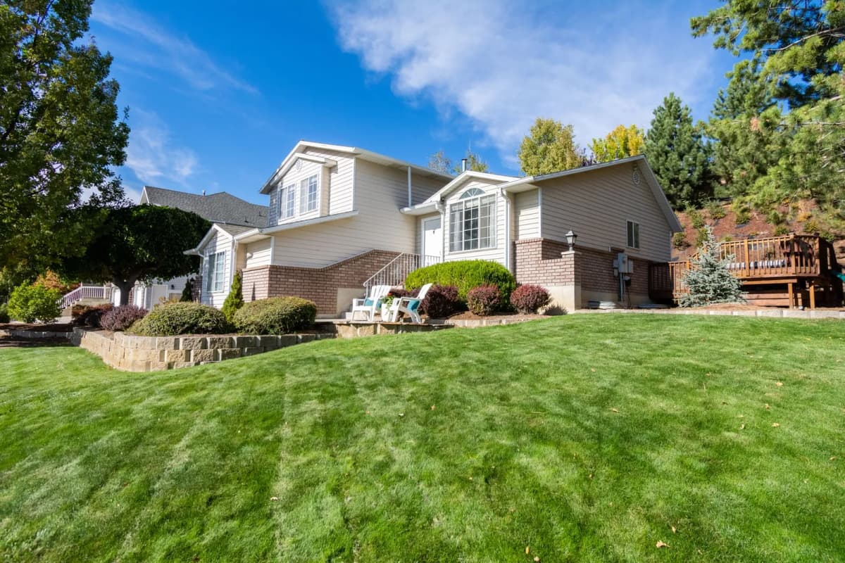 A two-story suburban home with a trimmed lawn and planted beds