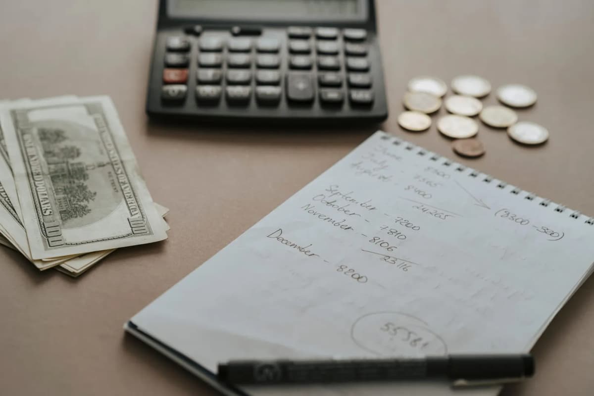 A calculator, cash and handwritten notes on a desk