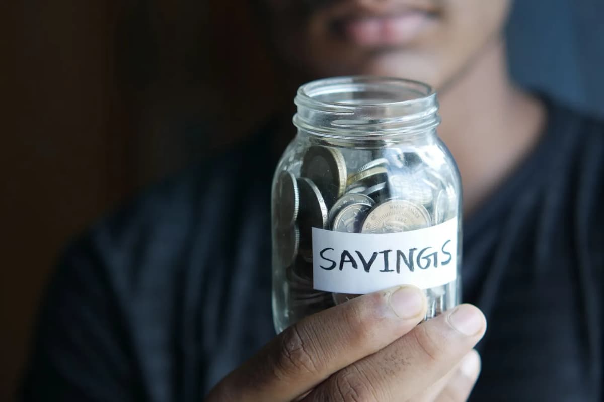 A hand holding a jar of coins