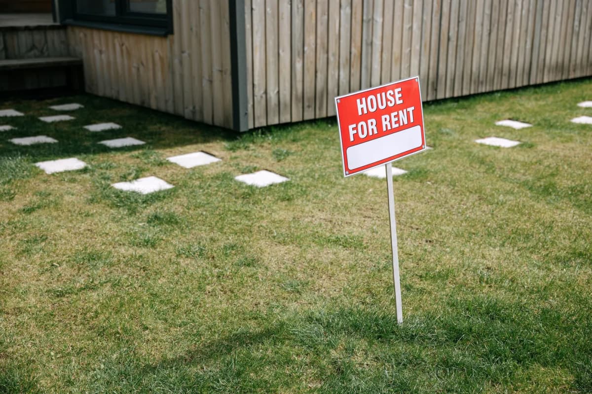 A House for Rent sign on the lawn of a single-family home