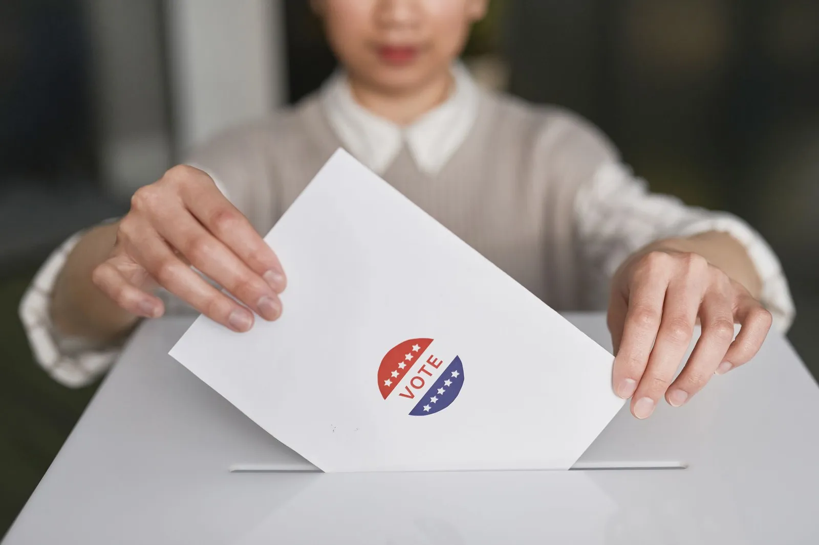 A person placing a paper ballot into a ballot box
