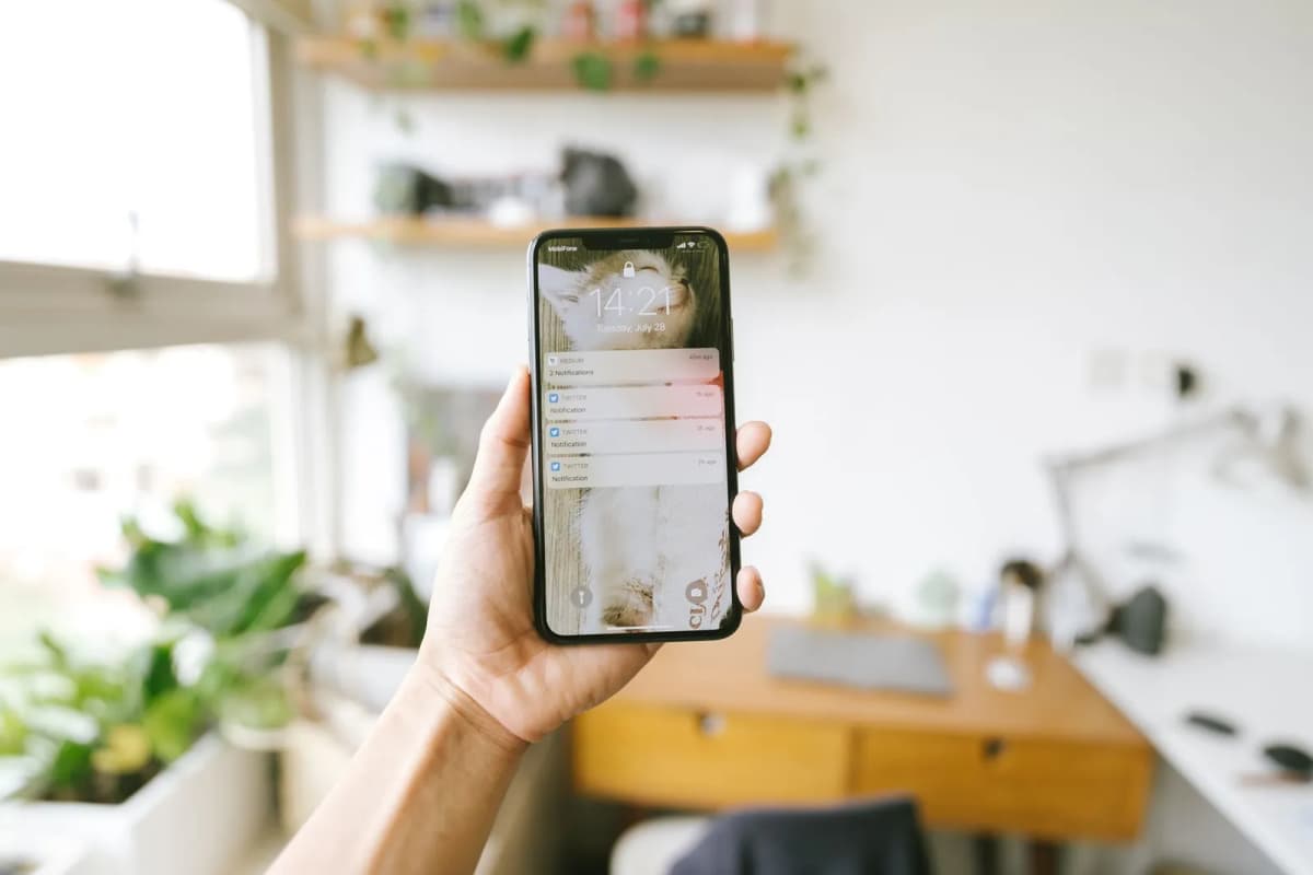 A hand holding a smartphone showing notifications on the lock screen