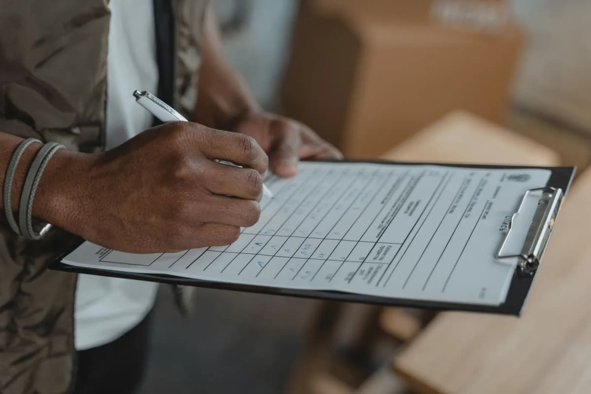 A person filling in a printed form attached to a clipboard