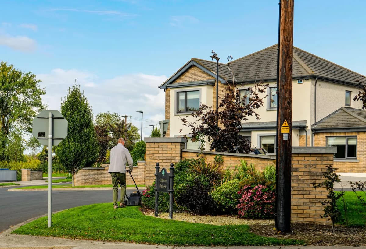 A man mowing the lawn outside a suburban home