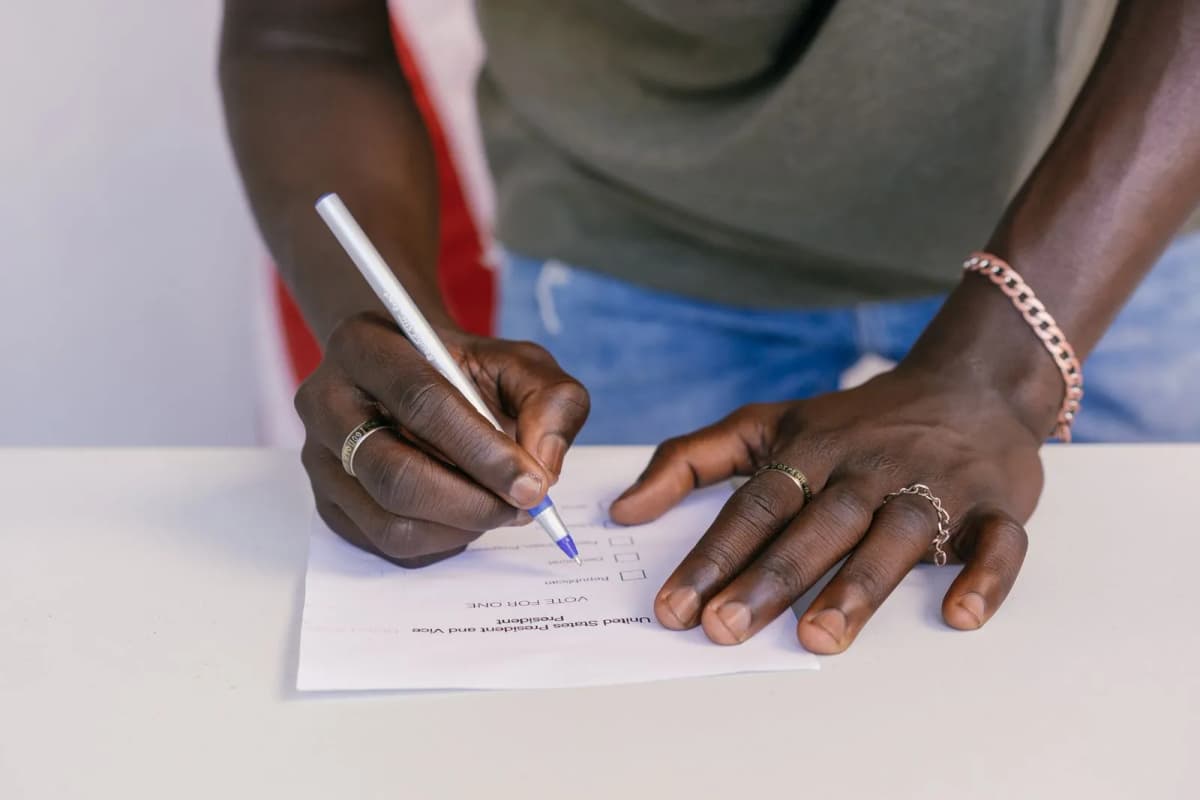 A close-up of a hand marking a ballot form with a pen