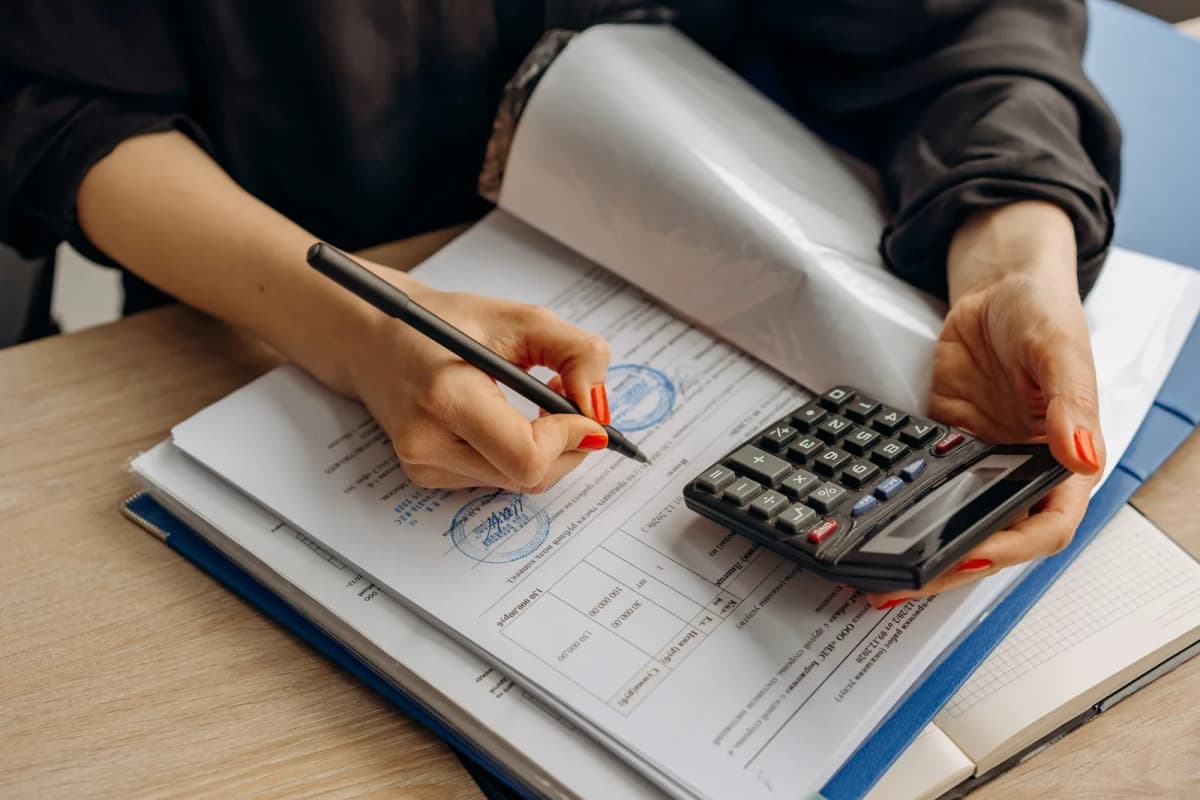 An accountant working through paperwork with a calculator