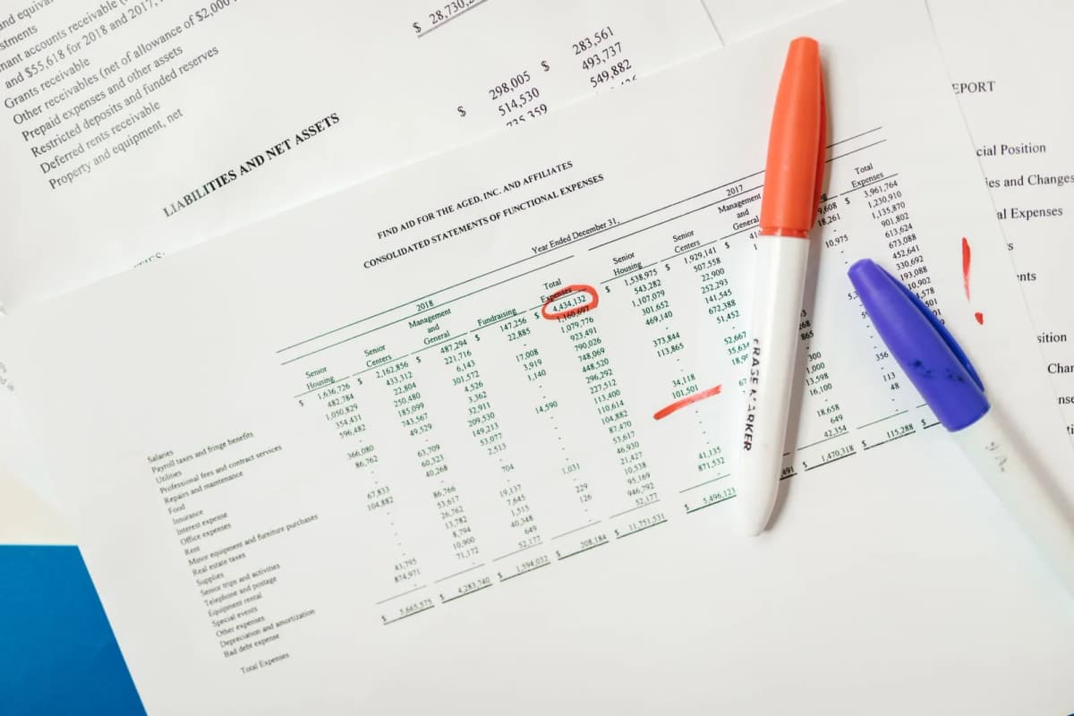 Financial documents with highlighted figures and marker pens