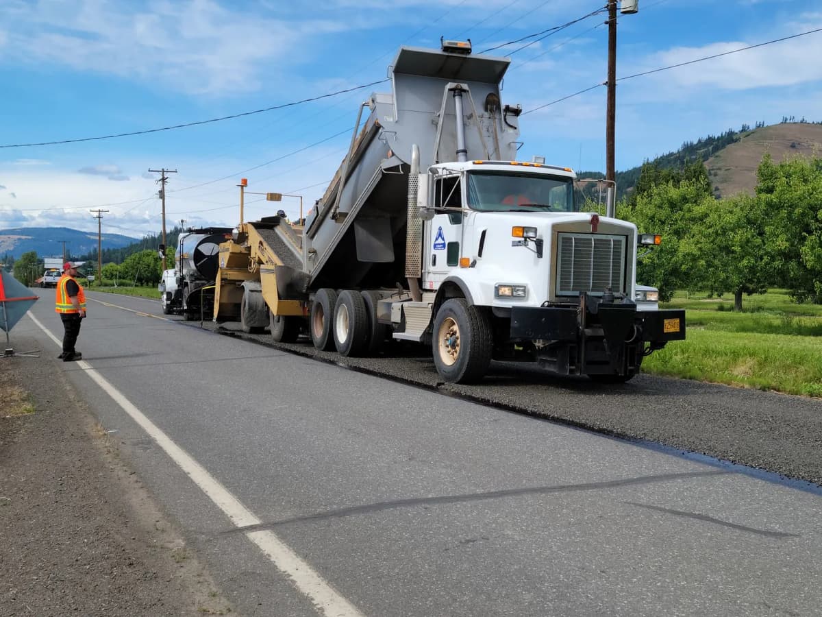 A paving crew and heavy equipment resurfacing a road