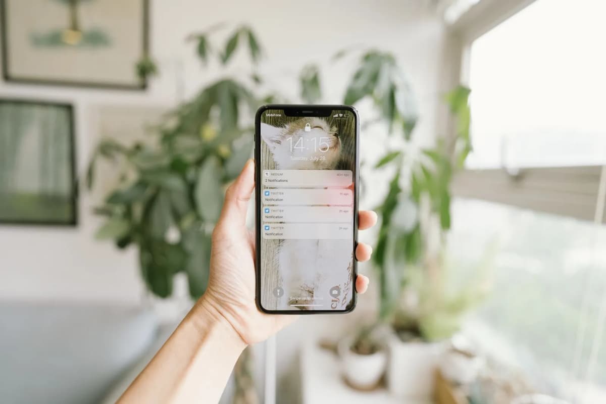 A hand holding a smartphone in a bright room at home