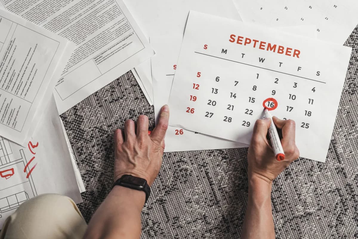 A calendar and paperwork spread out while somebody counts working days