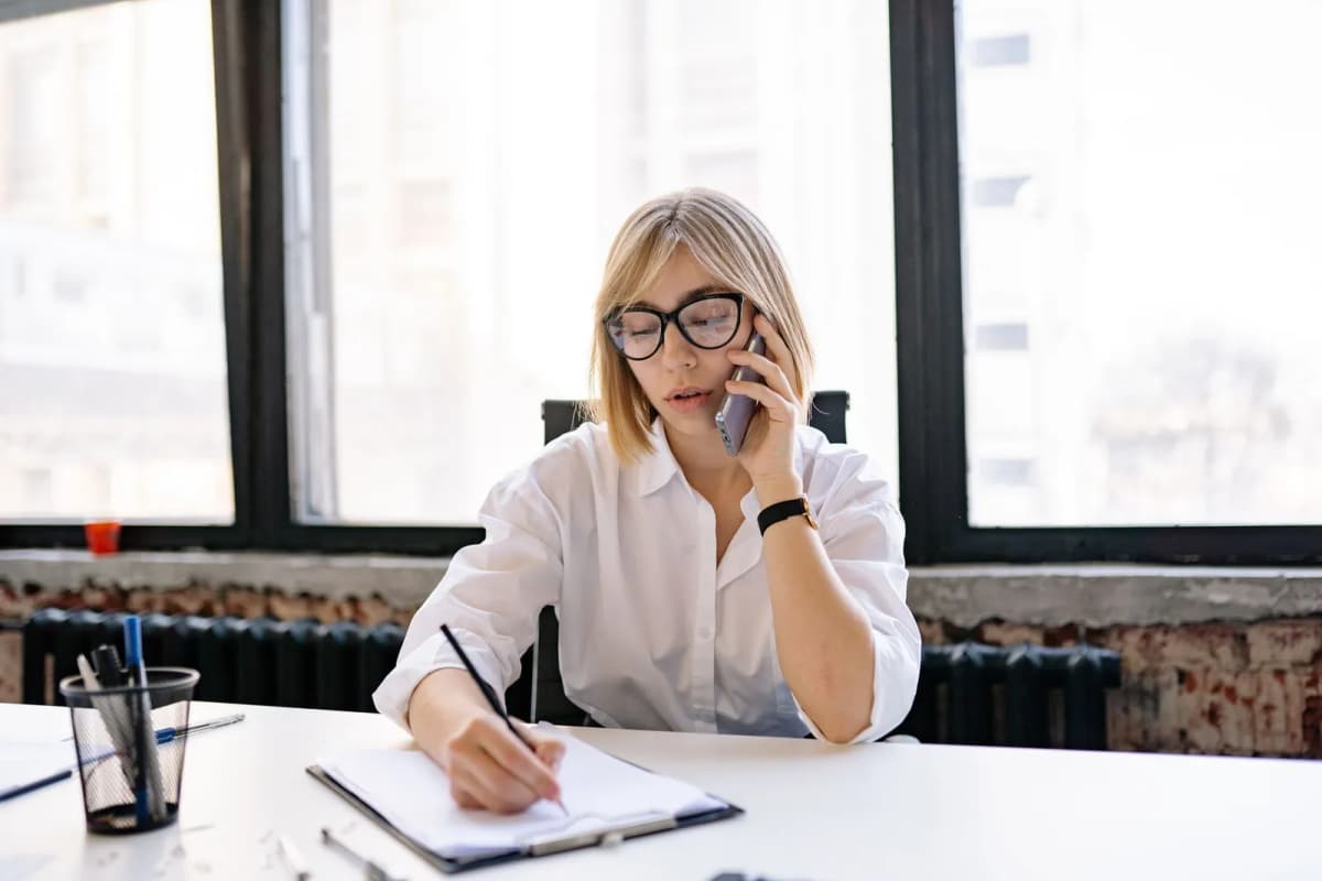 Somebody on a phone call taking notes at a desk