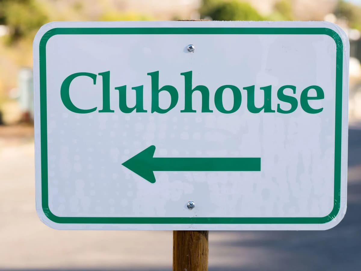 An outdoor directional sign pointing toward a community clubhouse